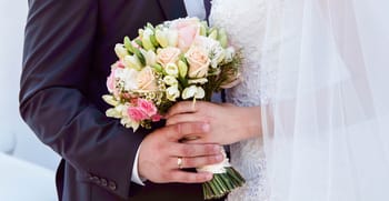 Couple marié tenant un bouquet de fleurs lors d'une cérémonie nuptiale.