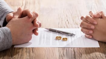 Deux personnes en discussion avec des alliances sur une table en bois.