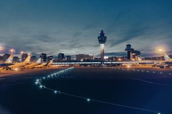 Vue nocturne de l'aéroport avec avions et tour de contrôle.