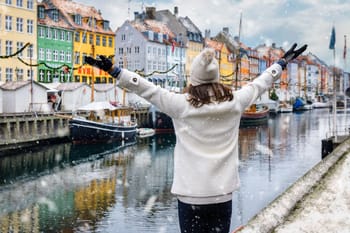 Femme admirant les maisons colorées de Copenhague sous la neige.