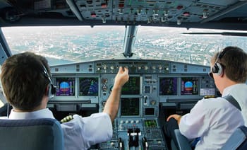 Pilotes dans le cockpit d'un avion en vol au-dessus d'une ville.