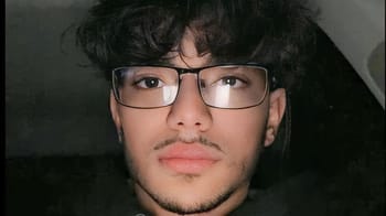 Jeune homme avec lunettes, regardant l'objectif, expression neutre.