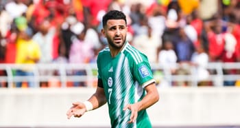 Riyad Mahrez en action sur le terrain avec un public en arrière-plan.