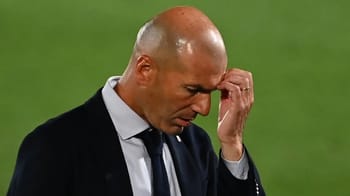 Zidane, entraîneur de football, en pleine réflexion sur le terrain.