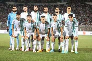 Groupe de joueurs de l'équipe d'Algérie en tenue de match sur le terrain.