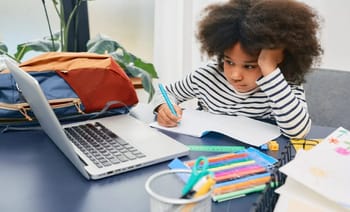Jeune fille studieuse avec ordinateur et fournitures scolaires.