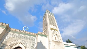 Mosquée tunisienne avec minaret sous ciel bleu clair.