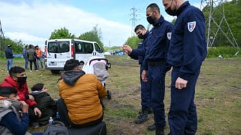 Policiers en uniforme contrôlant des migrants dans un champ.