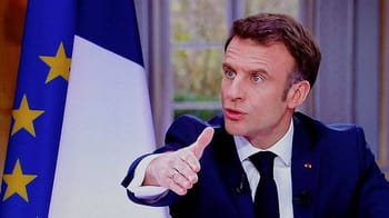 Le président français lors d'une interview avec drapeau européen et français en arrière-plan.