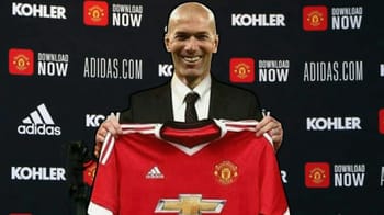 Zidane souriant tenant un maillot de Manchester United.