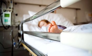 Enfant malade allongé dans un lit d'hôpital, visage endormi.