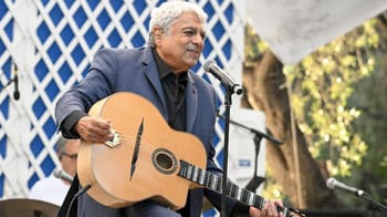 Enrico Macias jouant de la guitare lors d'un concert en plein air.