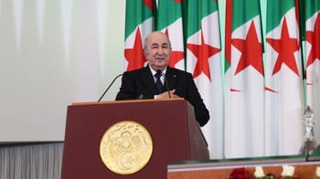 Président Tebboune parlant à un podium avec drapeaux algériens en arrière-plan.