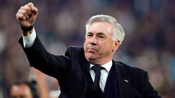 Carlo Ancelotti en tenue de coach, levant le poing sur le terrain.