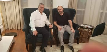 Deux hommes assis dans un salon, discutant.