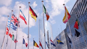 Drapeaux de plusieurs pays européens devant un bâtiment moderne en plein jour.
