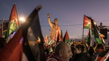 Manifestation avec drapeaux palestiniens et un orateur en plein discours.