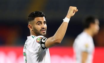 Riyad Mahrez célèbre avec un poing levé sur le terrain de football.