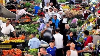 Foule dans un marché coloré avec fruits et légumes frais.