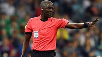Arbitre en action lors d'un match de football, signalant une faute.