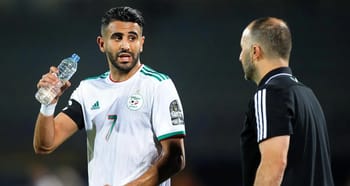 Mahrez en conversation avec un entraîneur lors d'un match de football.