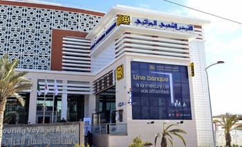 Bâtiment moderne de la banque CPA à Alger avec affichage numérique.
