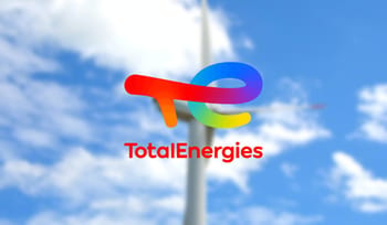 Logo de TotalEnergies contre un ciel bleu avec nuages blancs.