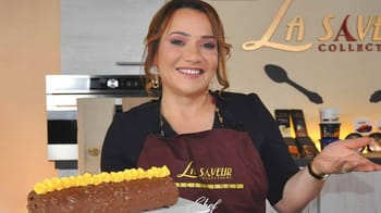 Chef avec un gâteau au chocolat décoré de fleurs jaunes.