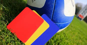 Ballon de football avec cartons jaune et rouge sur le terrain.