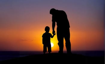 Silhouette d'un père et son fils tenant la main au coucher du soleil.