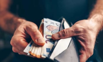 Main tenant un portefeuille avec des billets de banque en euros.