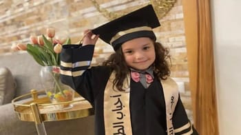 Jeune fille en robe de graduation souriante et tenant son chapeau de diplômée.