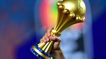 Main tenant un trophée de la CAN 2023 en or.