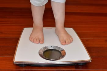 Enfant pesant sur une balance pour mesurer son poids.