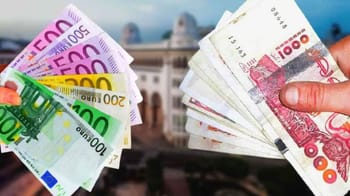 Échange de devises avec euros et dinar algérien en main.
