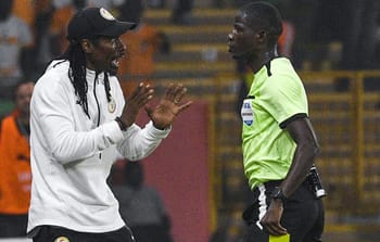 Arbitre et entraîneur discutant lors d'un match de football en Afrique.