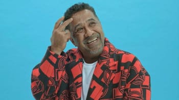 Cheb Khaled souriant, portant un blazer rouge et noir.