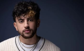 Jeune homme avec cheveux bouclés et barbe, portrait en studio.