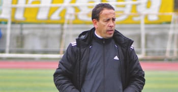 Entraîneur de football en pleine réflexion sur le terrain.
