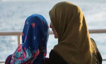 Deux femmes avec hijabs regardant l'eau, conversation sérieuse.