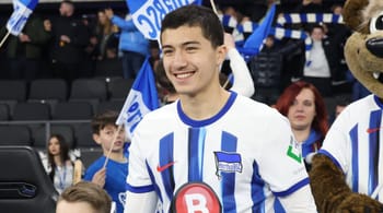 Ibrahim Maza en tenue de football avec supporters en arrière-plan.