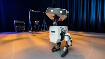Robot humanoïde sur scène avec éclairage dramatique et équipements techniques.