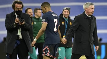 Kylian Mbappé serrant la main de l'entraîneur lors d'un match.