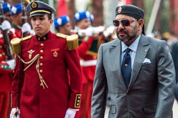Homme en costume avec lunettes et soldats en uniforme rouge.