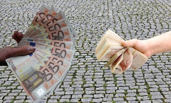 Deux mains échangeant des billets d'euros et de dinars algériens.