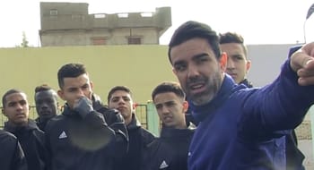 Vicente Girona s'adressant à un groupe de jeunes sportifs en extérieur.