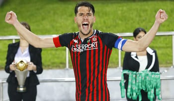 Footballeur en célébration avec maillot rouge et noir.