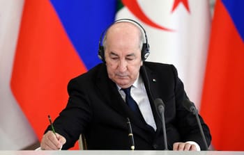 Tebboune lors d'une conférence avec drapeaux algérien et russe en arrière-plan.