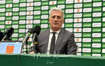 Homme en costume lors d'une conférence de presse sportive.