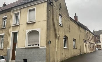 Façade d'une maison ancienne en France avec murs jaunis et fenêtres.